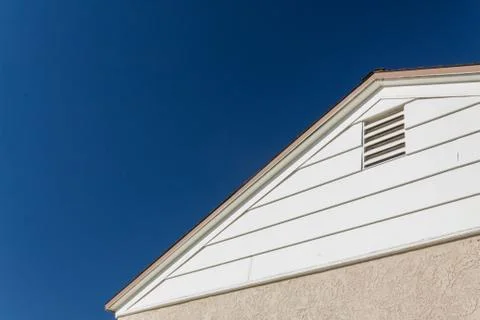 Generic house view of side and roof edge, stucco and vinyl with attic vent Stock Photos