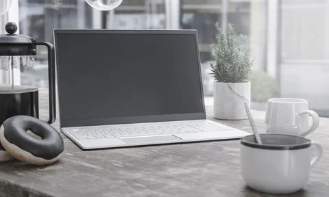 Generic laptop computer and coffee cup resting on wooden table. Blank screen  Stock Photos