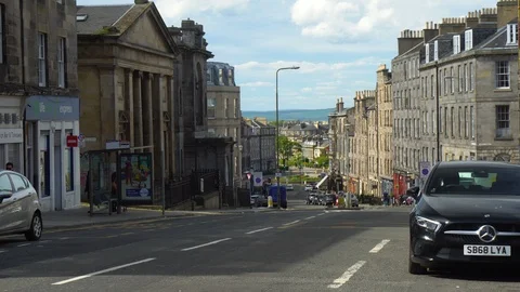Generic Main Street With Iconic Scottish Cobblestone House Exteriors and Traffic Stock Footage 121086092
