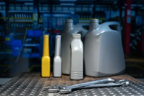 Generic plastic engine oil and chemical additive bottles on metal workbench.. Stock Photos