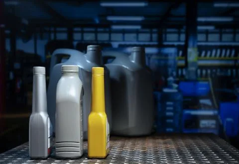 Generic plastic engine oil and chemical additive bottles on metal workbench.. Фото