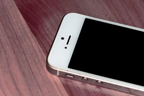 A generic smartphone lying on the table turned off with the black screen up Stock Photos