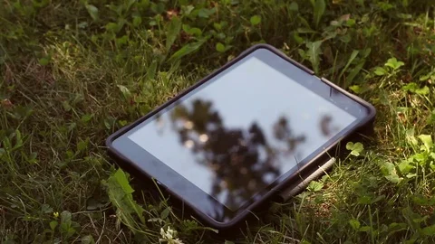 Generic Tablet resting in the grass on sunny day Stock Footage 78398902