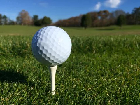 Generic white golf ball sit on tee over green grass on a golf course Stock Photos