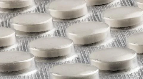 Generic white medical tablets in silver foil blister 库存照片