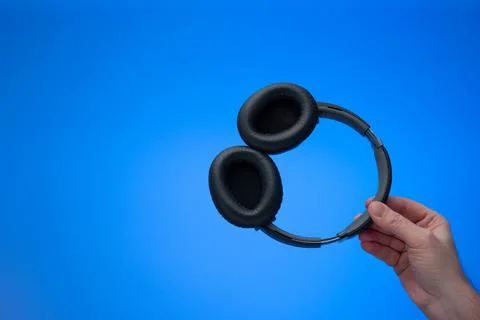 Generic wireless over the ear headphone held in hand by Caucasian male hand.  Stock Photos