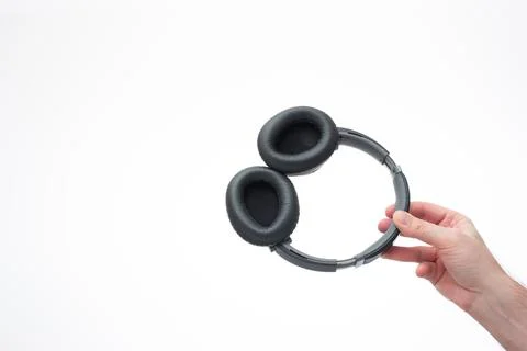 Generic wireless over the ear headphone held in hand by Caucasian male hand.  Fotos de archivo