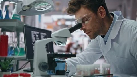 Genetics expert looking microscope making investigation in laboratory close up. Stock Photos