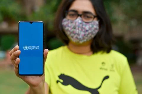 Geneva, Switzerland,2020. Girl wearing mask showing on her mobile phone scree Stock Photos