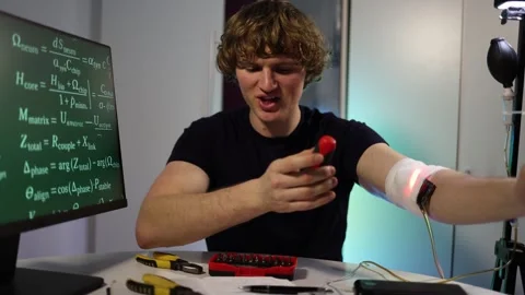 Genius engineer tests glowing arm implant in garage lab Stock Footage 324443081