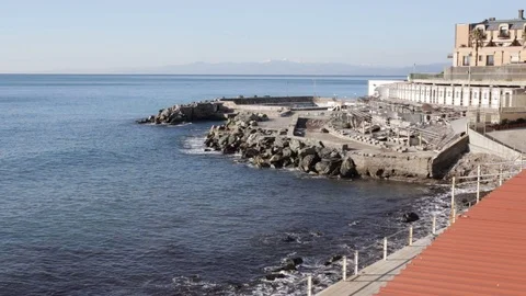 Genoa waves on the rocks in front of a bathing establishment in a sunny day Stock Footage 101924100