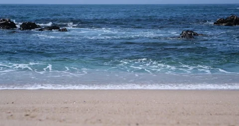 Gentle blue ocean waves breaking on sandy beach. Shallow depth of field. Video stock 151874870