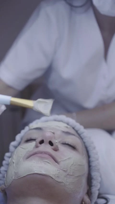 Gentle brush strokes apply clay mask along the cheek in calm facial ritual Stock Footage 342821015