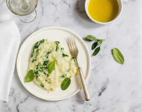 Gentle cream risotto with spinach, served with wine. Light background. Stock Photos