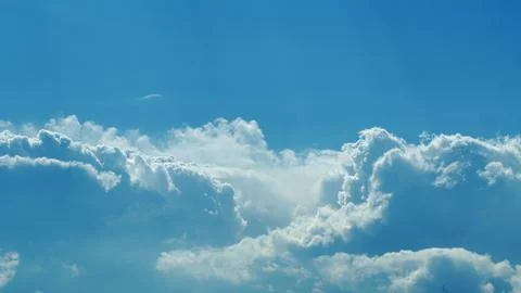 Gentle, Fluffy White Clouds Floating Gracefully Against a Clear, Vast Blue Sky A Stockfoto's