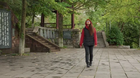 Gentle lady in red jacket ambles near temple inscription. Woman dressed in red Stock Footage 338077640