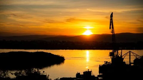 Gentle light of the setting sun on the river with a silhouetted crane in the sky Stock Photos