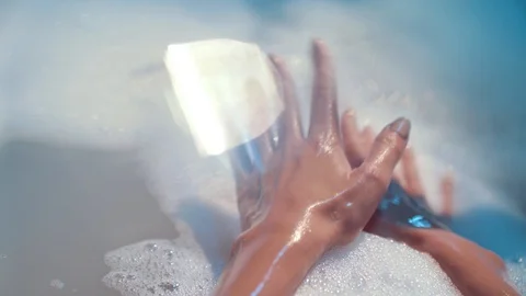 Gentle movements of hands in a soapy water during taking a nice bath Stock Footage 129710491