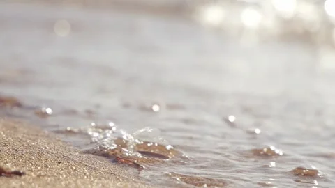 Gentle ocean waves crash softly onto the warm sandy beach Stock Footage 337411292
