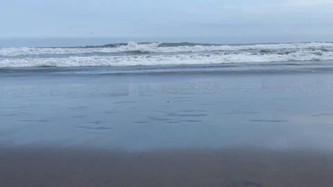 Gentle Ocean Waves Crashing on a Sandy Beach Shore Under a Cloudy Sky Stock Footage 340256974