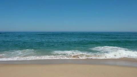 Gentle ocean waves crashing onto a sandy beach 動画素材 345637790