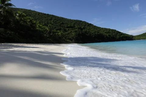 Gentle ocean waves foaming onto a pristine sandy beach Stock Photos