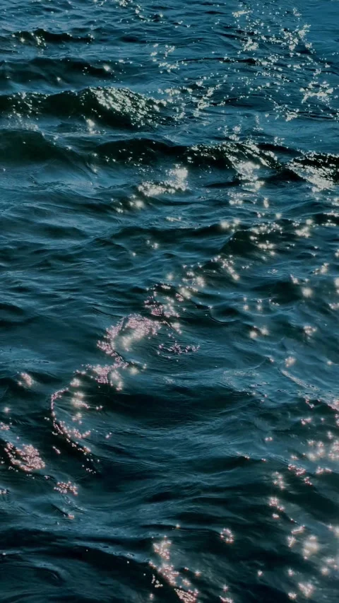 Gentle ocean waves with golden sunlight reflections on blue water Stock Footage 346612078