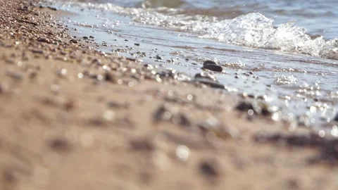 Gentle ocean waves lap softly onto a sandy pebble beach. Stock Footage 337409659