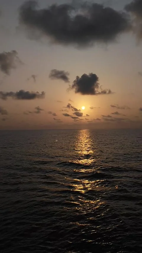 Gentle ocean waves reflect the setting sun in this beautiful video clip Stock Footage 344369092