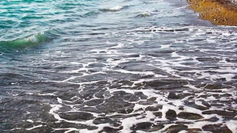 Gentle ocean waves rolling onto dark sandy shore with white foam and turquo.. Stock-Footage 348275771