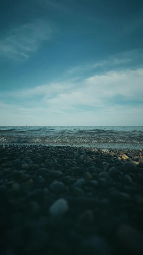 Gentle ocean waves rolling onto a pebble beach low angle Stock Footage 346275262