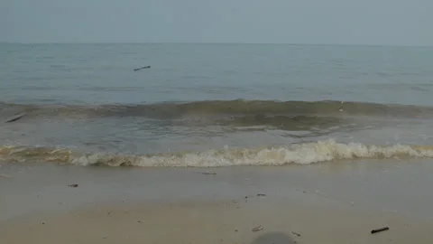 Gentle ocean waves rolling onto a sandy beach under an overcast sky Stock Footage 344601425
