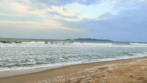 Gentle Ocean Waves Touching Sandy Beach with Distant Island Under Blue Sky Stock Footage 318784340