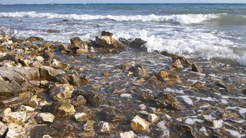 Gentle ocean waves wash over a rocky coastal beach shore. Stock Footage 337413208