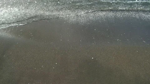 Gentle ocean waves washing dark black volcanic sand beach. Stock Footage 311468601
