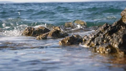 Gentle ocean waves washing over rugged rocks on the shore. Stock Footage 337406852