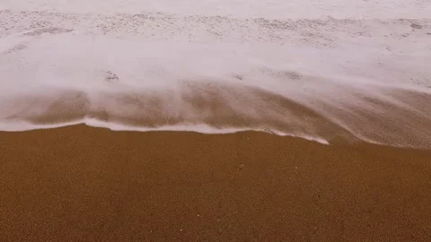Gentle ocean waves washing over sand on beautiful sunny coastal beach shore. Video stock 344712384