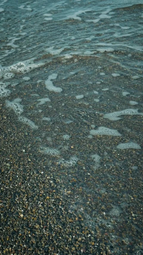 Gentle ocean waves washing over a pebble beach top-down 库存影片 346275330