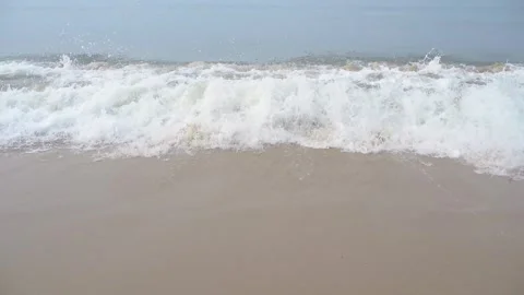 Gentle ocean waves washing onto a sandy beach during a calm day 動画素材 342027532