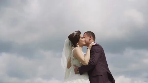 Gentle posing bride and groom on the background of clouds. Slow motion Stock Footage 233524746