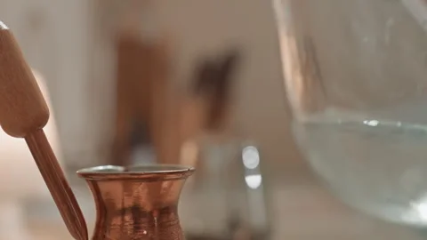 Gentle pour in copper cezve. Closeup of metal pour and blurred background Stock Footage 342064889