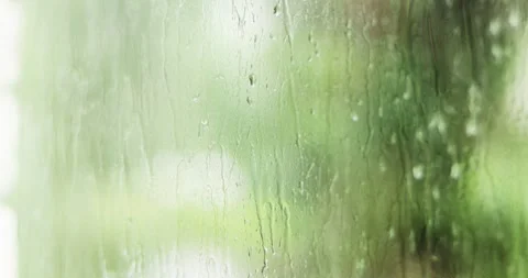 Gentle rain falling on a window with a blurred green backdrop Stock Footage 339074435