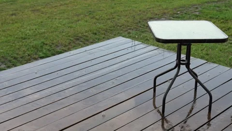 Gentle rain falling on a wooden deck and table Stock Footage 338384617