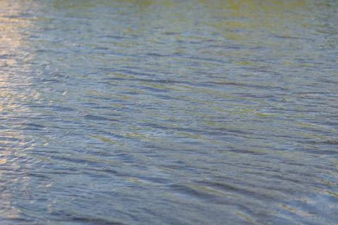 Gentle ripples dance across the surface of a serene lake at sunset, capturi.. Stock Photos