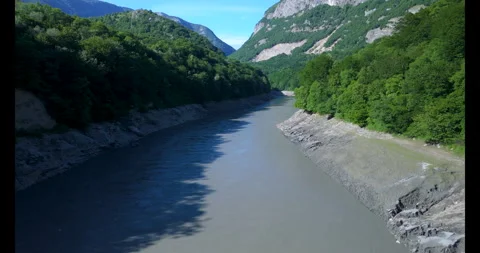 Gentle river flows through lush green valleys and rugged mountains in a serene Video stock 314083483