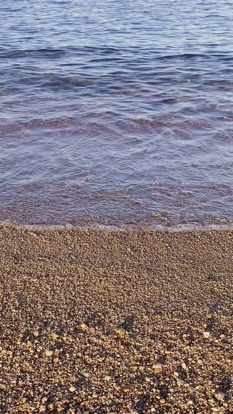 Gentle sea waves lapping over pebble beach shore at sunset. Warm orange glow  Stock Footage 329416090