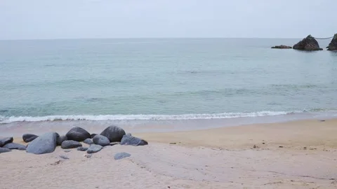 Gentle sea waves lapping on sandy beach with smooth rocks Stock Footage 338193949