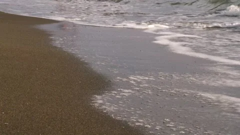 Gentle sea waves rolling onto the sandy beach in slow motion Видео 284667083