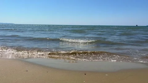 Gentle Sea Waves Rolling onto Sandy Beach Under Clear Blue Sky Stock Footage 310232764
