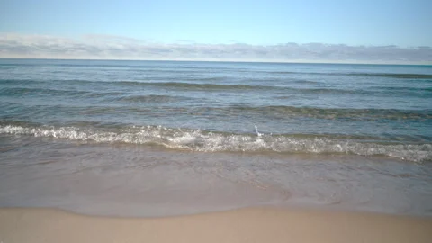 Gentle sea waves rolling onto a sandy shore on a beautiful, tranquil day with a 库存影片 336702176